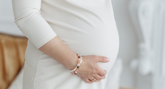 Image of pregnant woman touching her belly with hands. Close-up shot